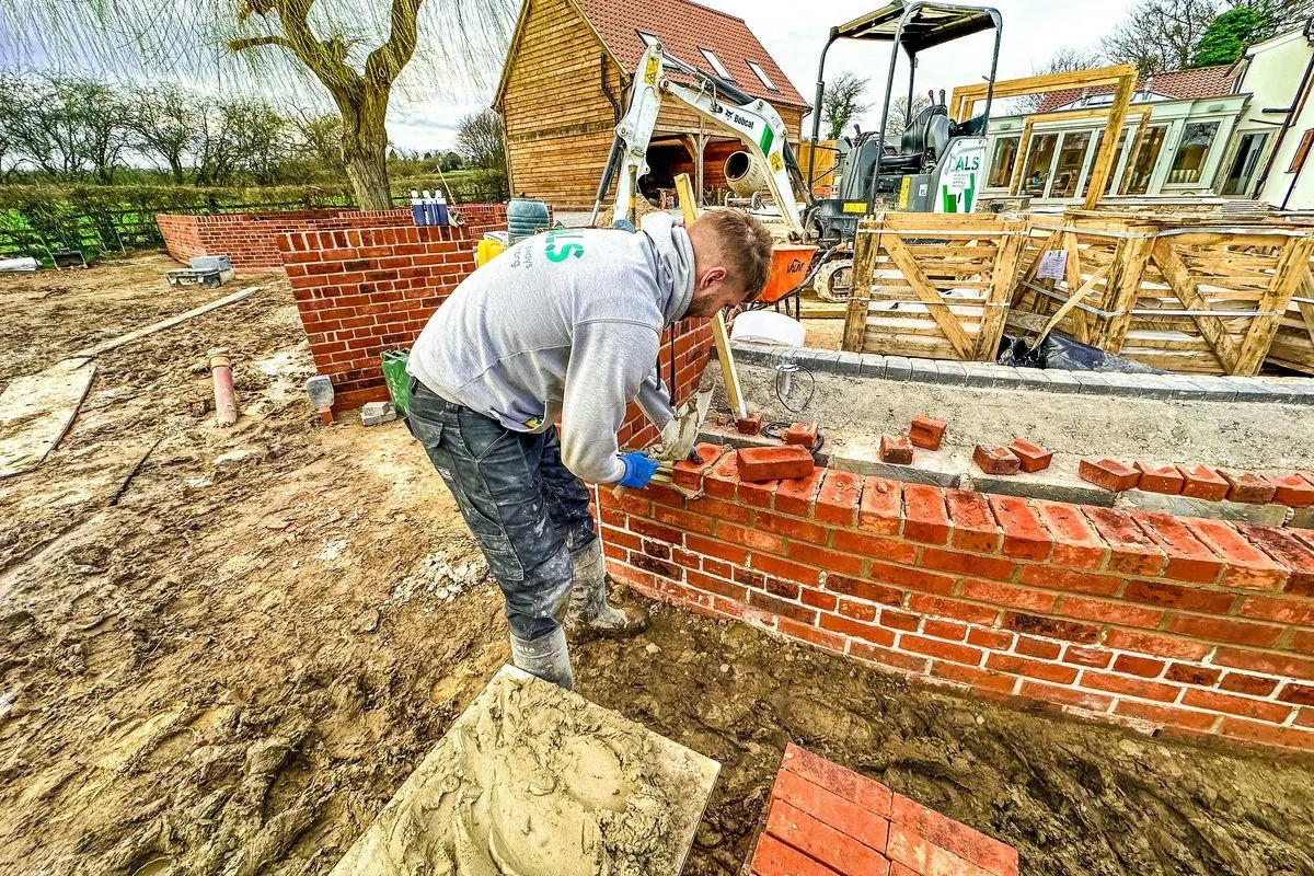 Jamie Pell laying red bricks to build a curved garden wall