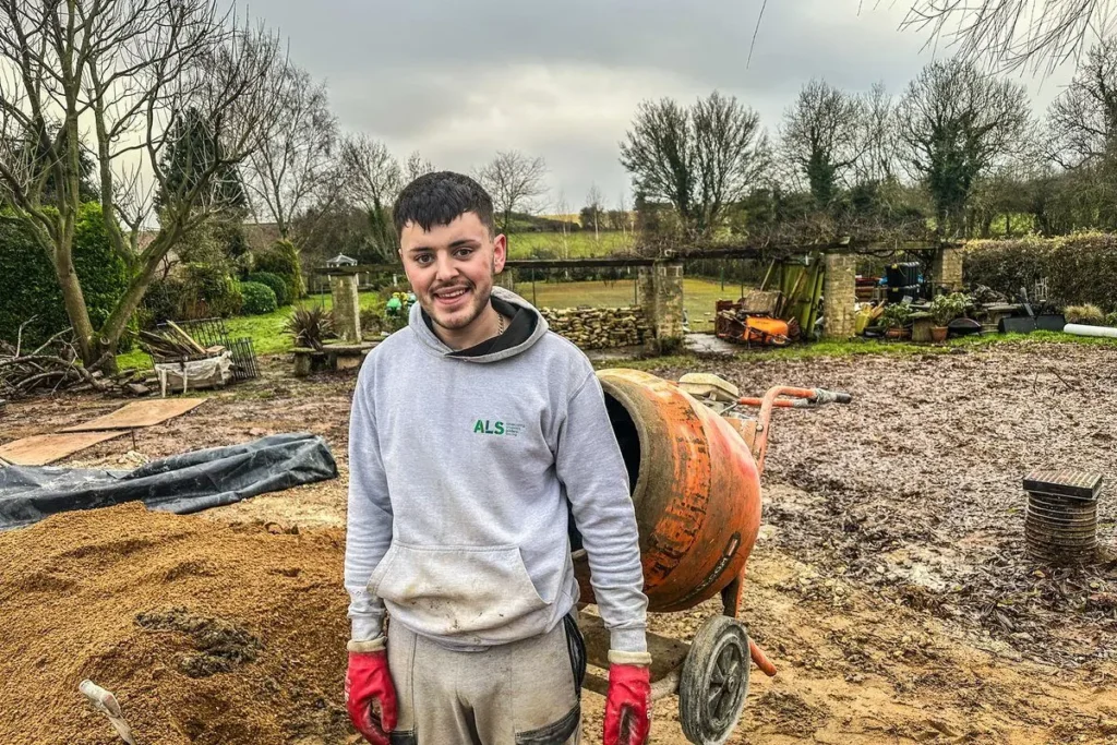 Ryan Fiske standing by a cement mixer on a garden build