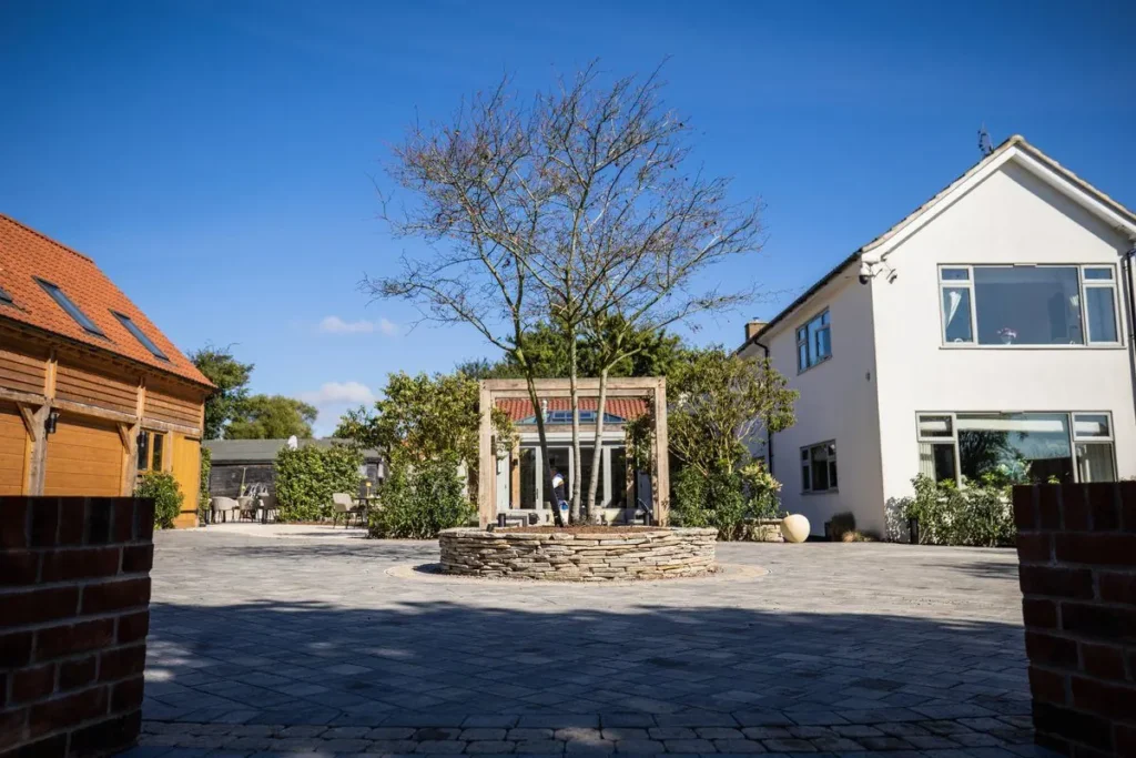 Grey block-paved courtyard drive with a circular dry-stone tree bed