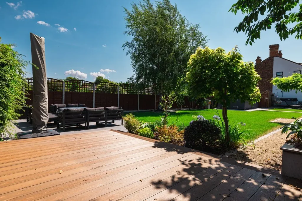 Warm brown composite decking with a dark aluminium sofa set and covered parasol