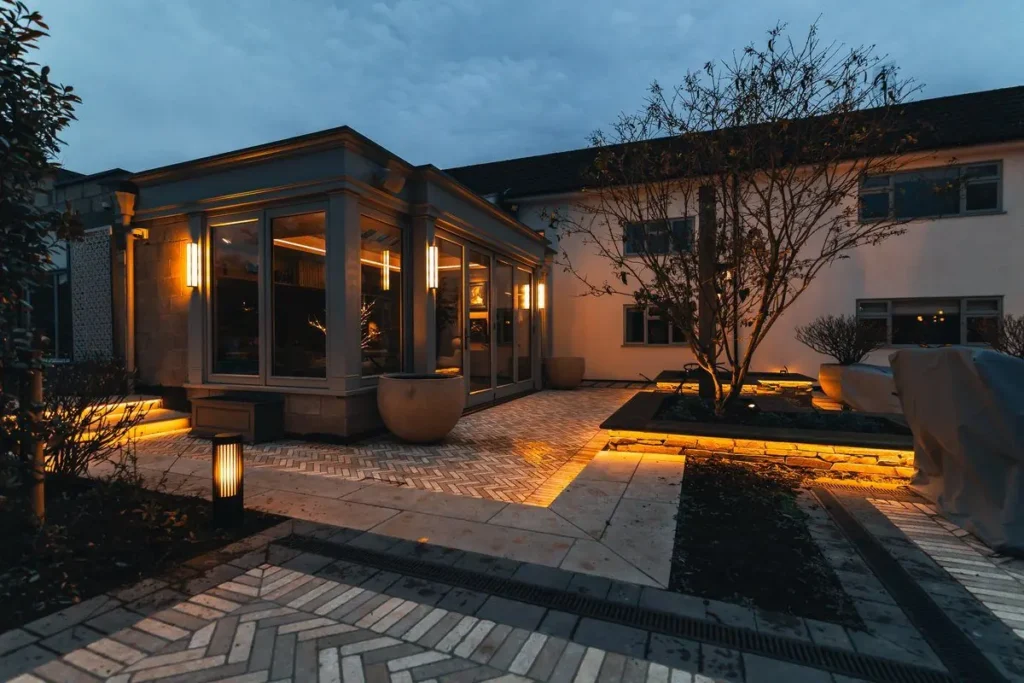Herringbone patio with warm LED strip lighting under raised bed copings at dusk