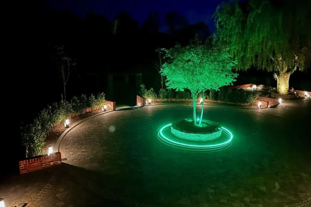 Circular block-paved drive at night with an uplit central tree and low bollard lights