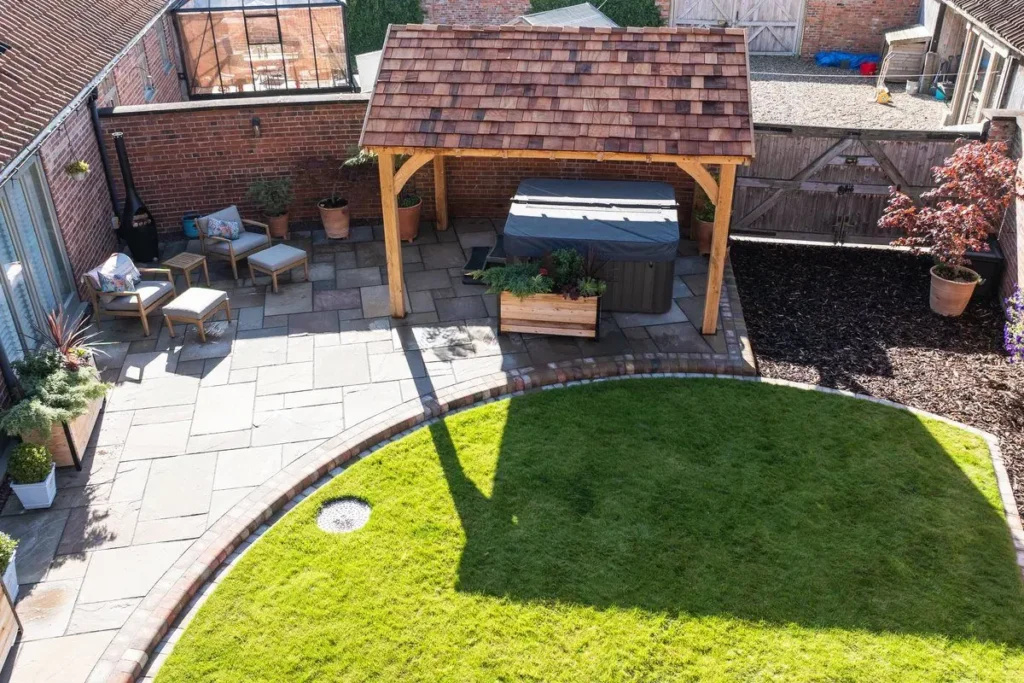 Sandstone patio with armchairs and an oak-framed gazebo over a hot tub