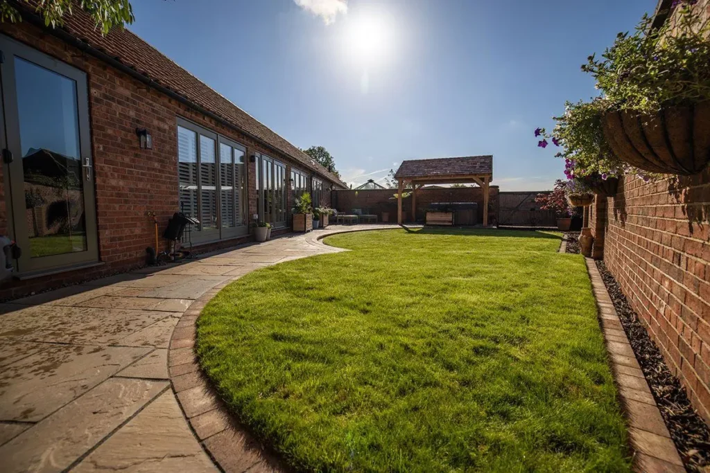 Long curved lawn edged with buff natural stone paving