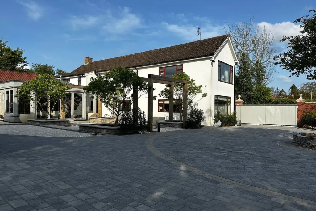 White house with orangery, oak pergolas and multi-stem trees in stone planters