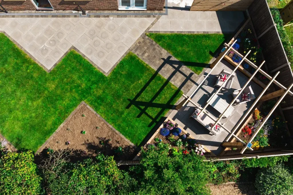 Overhead view of a timber pergola over seating beside a zig-zag lawn and grey patio