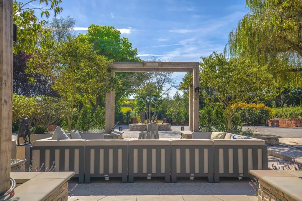 Cream outdoor sofa on a stone terrace framed by an oak pergola