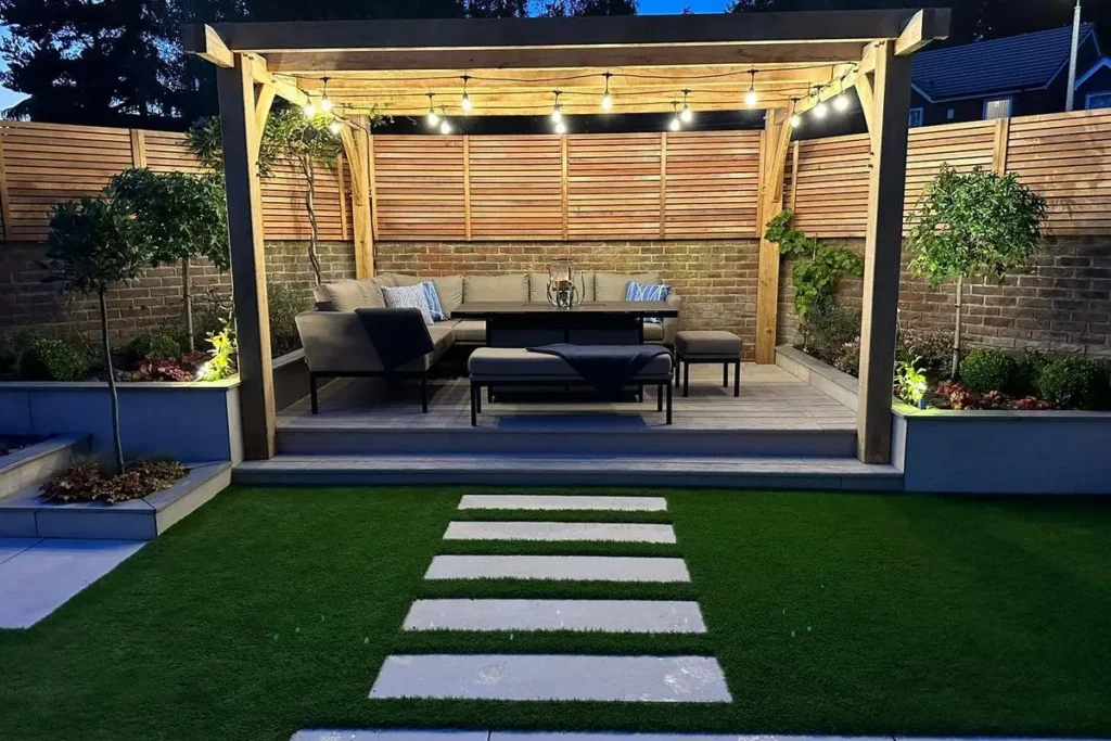 Oak-framed pergola with festoon lights over a raised porcelain platform at dusk