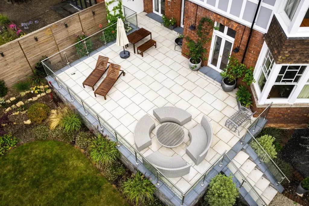 Raised porcelain patio with glass balustrade and circular rattan sofa