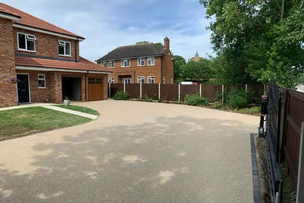 Large buff resin-bound driveway in front of a red-brick detached house
